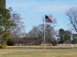 Image: American flag flying with white fence in background